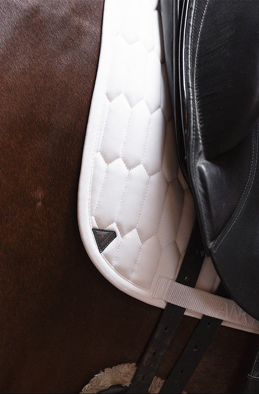 Close-up of a white quilted saddle pad on a brown horse.