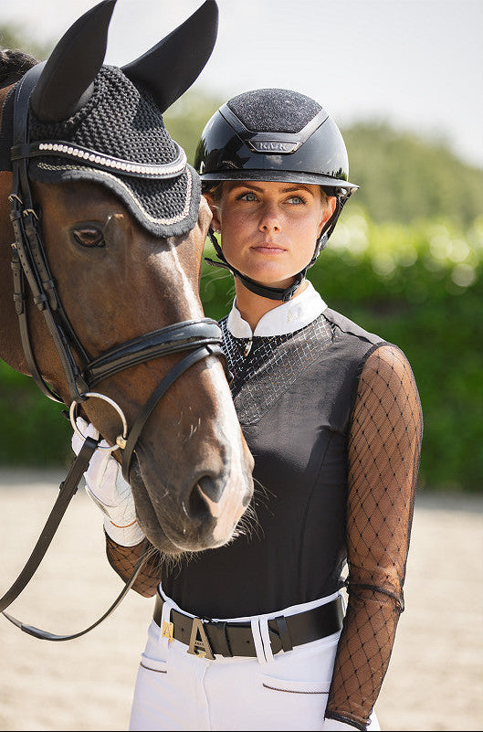 Woman in equestrian attire standing next to a horse with ANKY shirt and Kask helmet