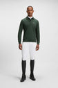 Man wearing the Boss Equestrian Dark Green Polo Sweater with white breeches