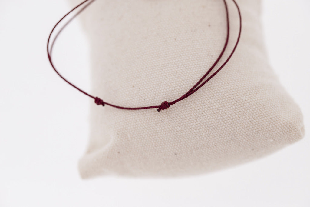 Adjustable horse logo bracelet with fine cord and elegant gold-plated detail.