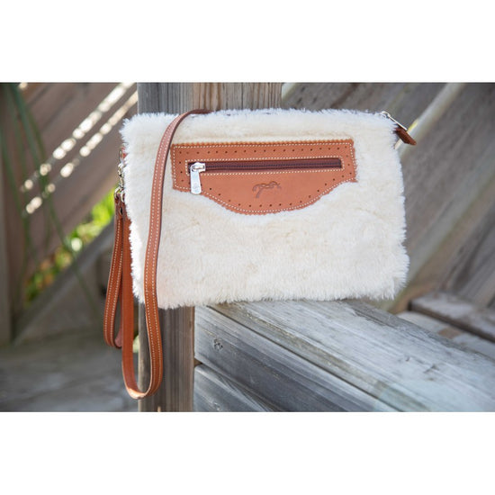 Leather and faux fur crossbody pouch with zip closure and detachable handle for elegant winter styling.