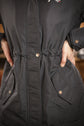 Long winter riding jacket with rear slit and adjustable waist for comfortable equestrian wear.