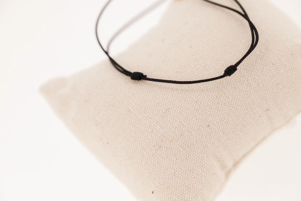 Penelope Collection gold cord bracelet with signature horse logo on a round plate.
