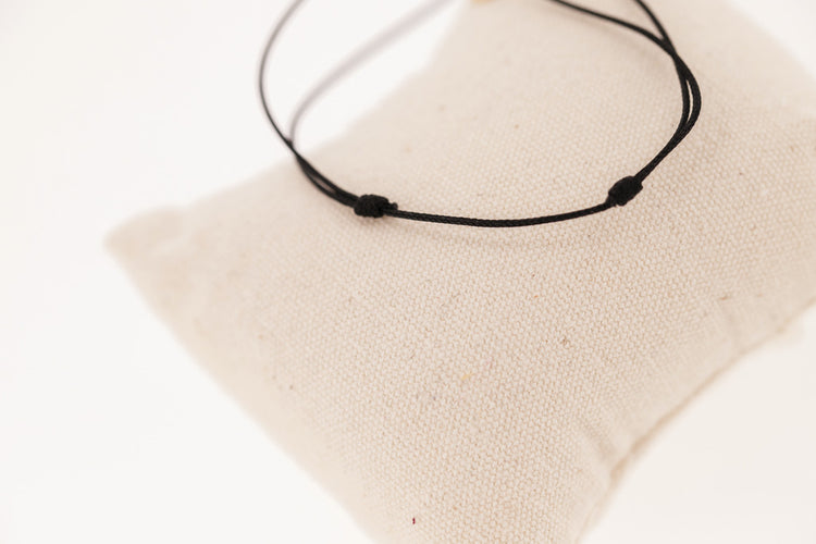 Penelope Collection gold cord bracelet with signature horse logo on a round plate.
