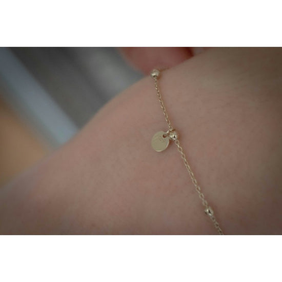 Penelope Eugénie Bracelet with gold beads, delicate tassels and signature round logo plate.