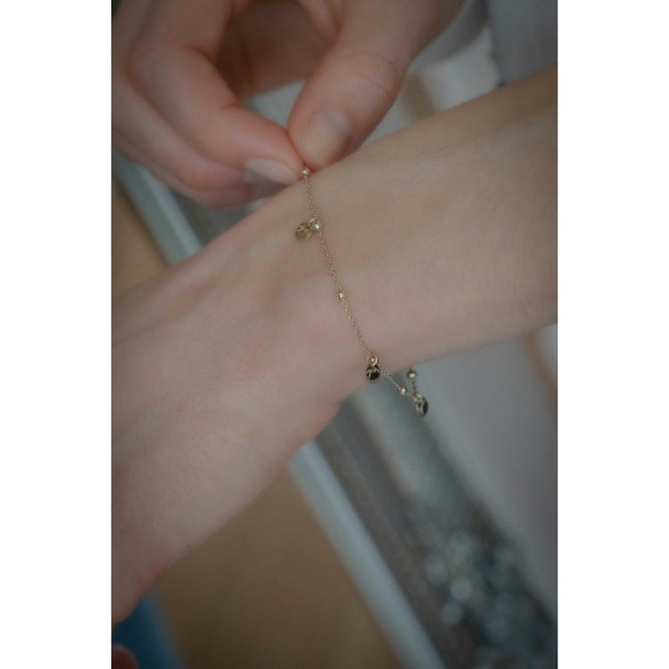 Penelope Eugénie logo bracelet with small golden beads and decorative tassels.