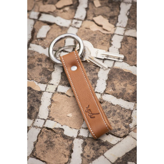 Penelope leather equestrian keychain with contrasting cream saddle stitching.