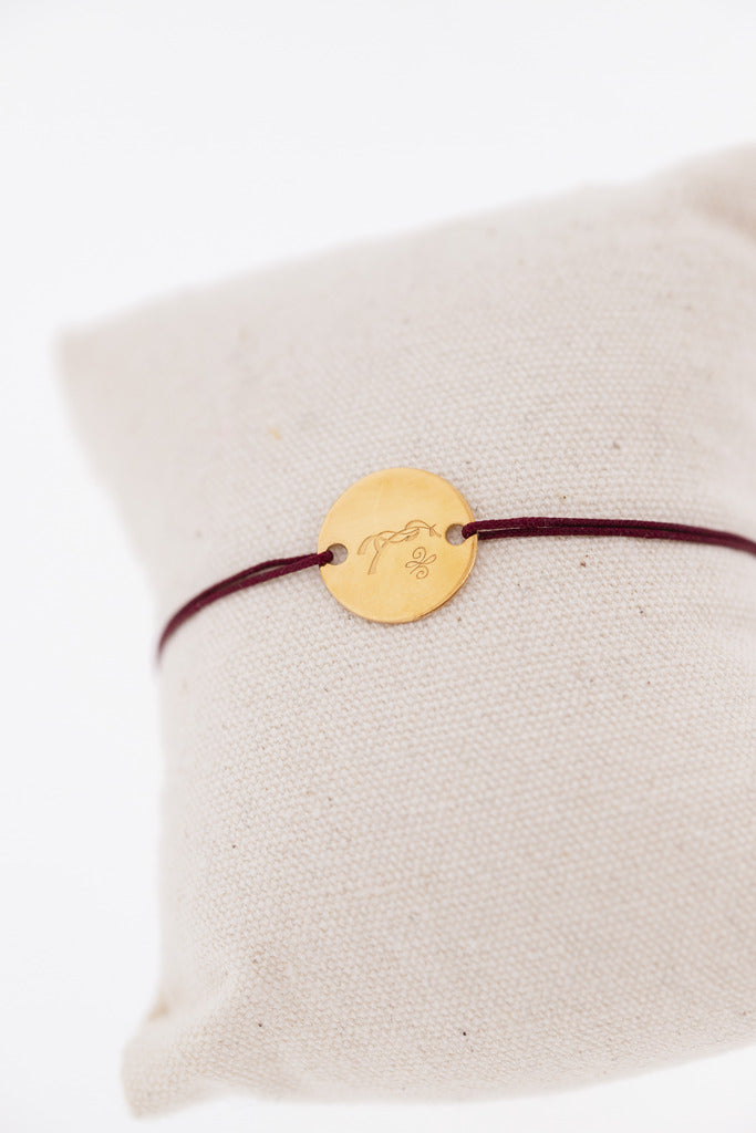 Penelope Zoe delicate gold bracelet with adjustable cord and signature equestrian horse logo detail.