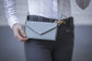 Perforated leather phone bag with compact envelope-style design for everyday essentials.