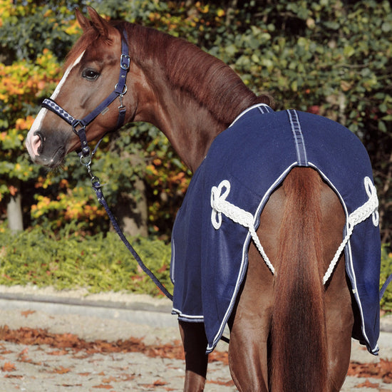 Warm fleece cooler rug, light and with excellent moisture transport. Breast buckle with overlying chest flap, which can be opened with a velcro fastener and is completely removable. Decorative cord on the tail strap. Also ideal as a sponsor or advertising rug, as the rug offers plenty of space for embroidery on the breast flap and in the flank area.